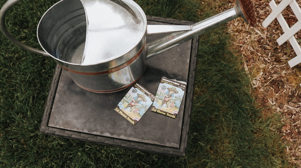 Watering can and seeds for garden sit on a table in the yard